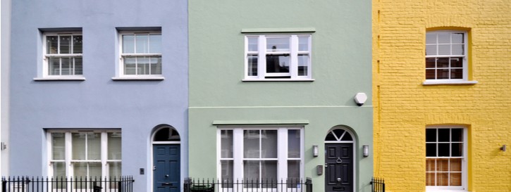 A row of three terraced townhouses painted blue, green and yellow